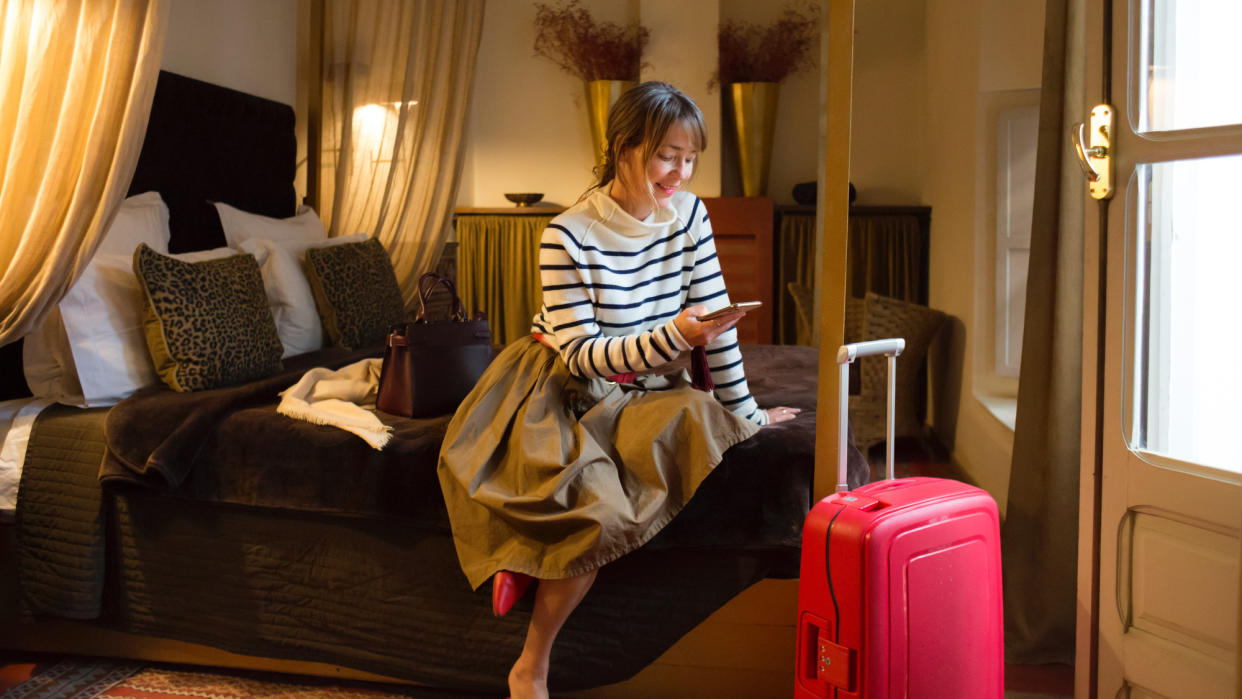  Woman in hotel room with suitcase. 
