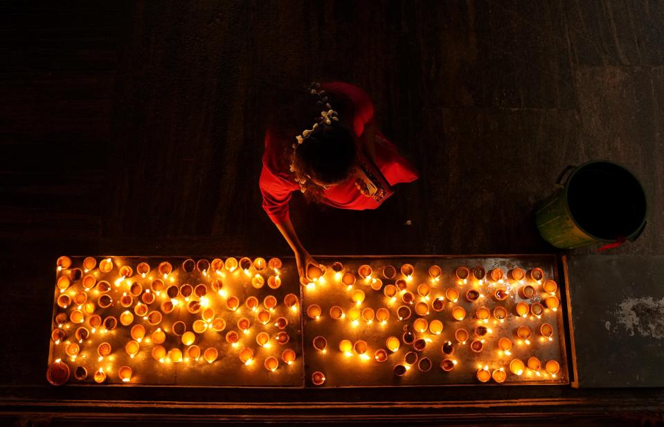 An ethnic Tamil woman prays holding a tray of oil lamps during Diwali, the Hindu festival of lights, in Colombo, Sri Lanka, Thursday, Nov. 4, 2021. Millions of people across Asia are celebrating the Hindu festival of Diwali, which symbolizes new beginnings and the triumph of good over evil and light over darkness. (AP Photo/Eranga Jayawardena)