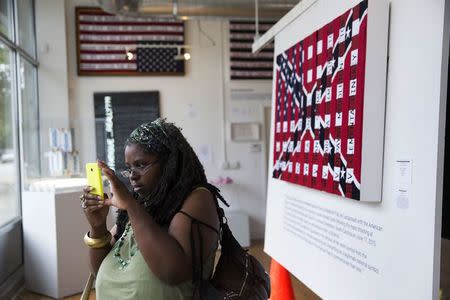 Mary Watkins, who travelled from Milwaukee, Wisconsin to view the exhibit, takes pictures of artwork from artist Ti-Rock Moore at Gallery Guichard in Chicago, Illinois, July 14, 2015. REUTERS/Andrew Nelles