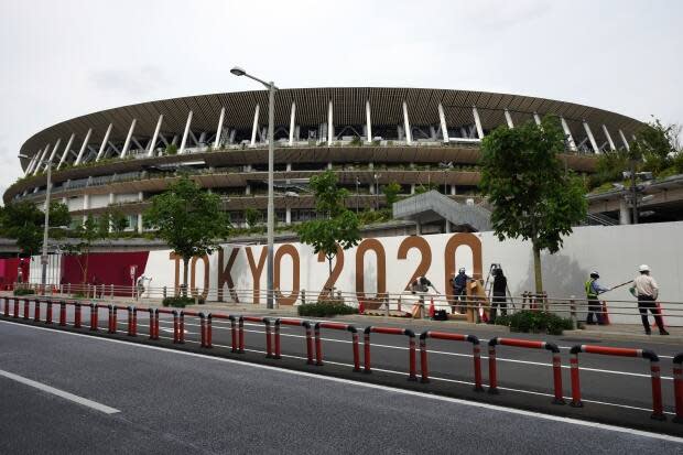 Workers paste the overlay on the wall of the National Stadium, where the opening ceremony and many other events are scheduled for the Tokyo Games. (Eugene Hoshiko/The Associated Press - image credit)