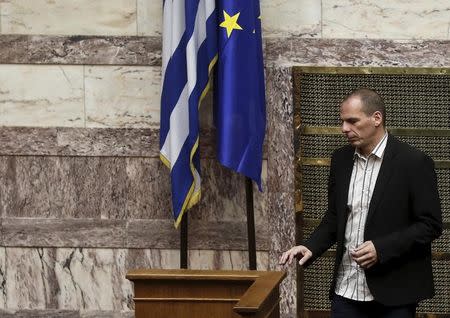 Greek Finance Minister Yanis Varoufakis walks next to a European Union and a Greek national flag during a parliamentary session in Athens April 2, 2015. REUTERS/Alkis Konstantinidis