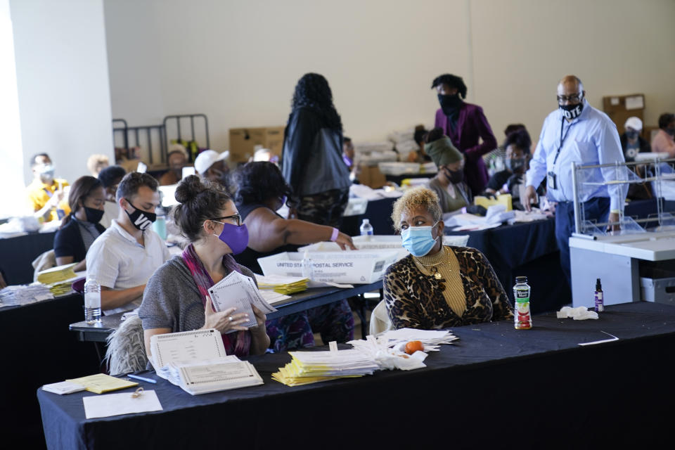 An election worker handles ballots as vote counting in the general election continues at State Farm Arena on Thursday, Nov. 5, 2020, in Atlanta. (AP Photo/Brynn Anderson)