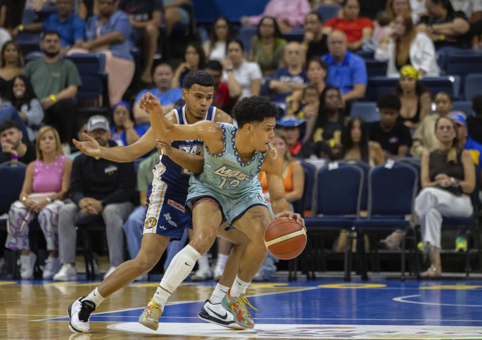 Guaynabo Mets Jermaine Miranda dribbles the ball against Bayamón Vaqueros Bryan Gonzalez during their basketball game at the Ruben Rodríguez Coliseum in Bayamón, Puerto Rico, Monday, July 1, 2024. Puerto Rico’s professional basketball league is experiencing a renaissance thanks to reggaeton stars like Bad Bunny, Ozuna and Anuel AA, who are stepping into the financial game, buying local teams and helping to stack up a loyal fan base. (AP Photo/Alejandro Granadillo)