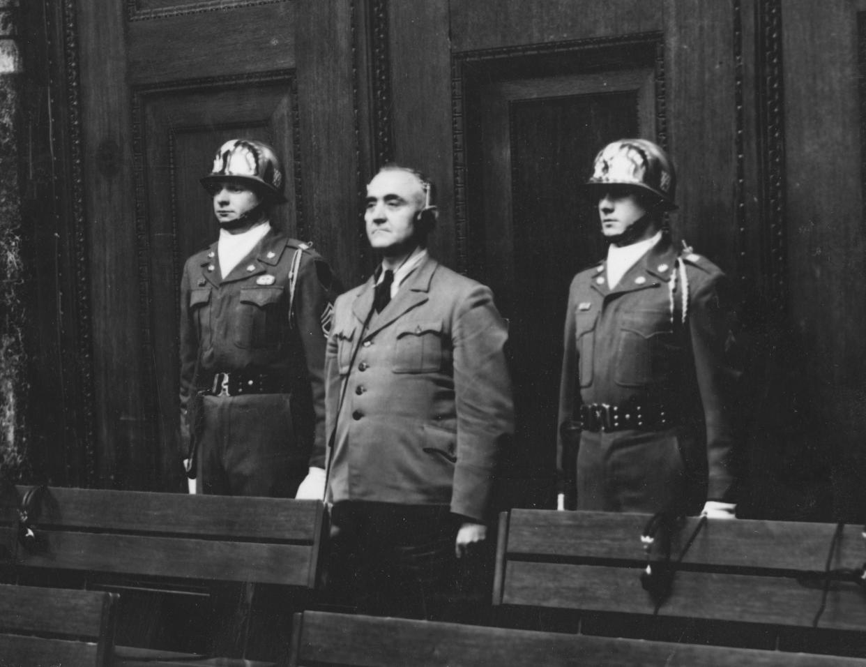 FILE - In this April 14, 1949 file photo, defendant Gottlob Berger, former chief of the SS head office, is sentenced to 25 years imprisonment, flanked by Sgt. 1st class Thomas H. Andress from Palestine, Texas, member of the honor guard 16th inf., left, and an not identified honor guard in Nuremberg, Germany. Germany marks the 75th anniversary of the landmark Nuremberg trials of several Nazi leaders and in what is now seen as the birthplace of a new era of international law on Friday, Nov. 20, 2020. (AP Photo/Albert Riethausen, file)