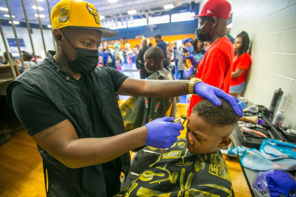 K.J. Dorsey, 10, gets a free haircut from Devon Slater on Saturday during the Stop the Violence Back to School Rally at Santa Fe College in Gainesville.