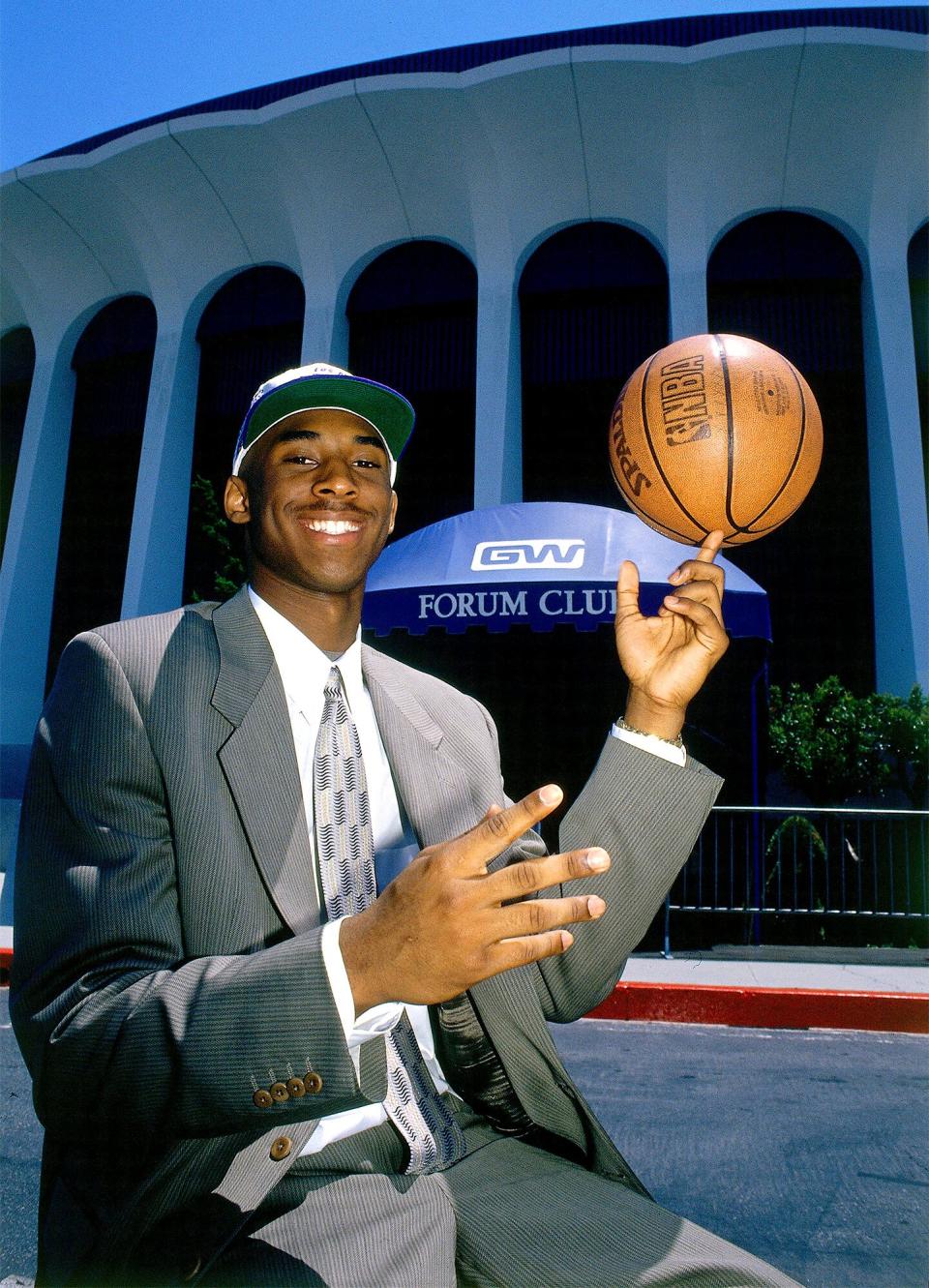 After earning his No. 8 Lakers number, Bryant is seen grinning while posing with a basketball outside the Forum in Inglewood, California, in 1997.