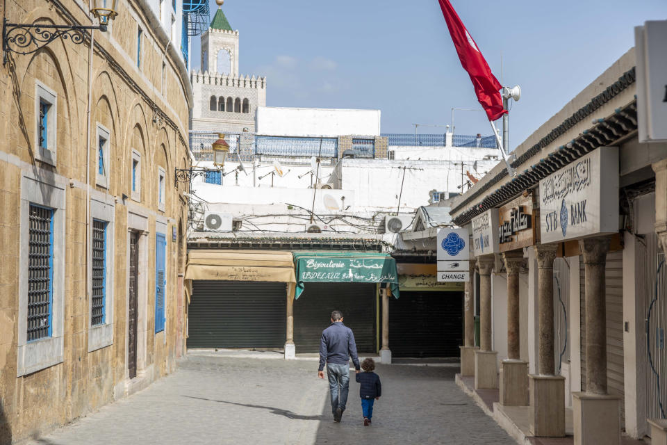 Tunis: Ein Mann und sein Kind gehen durch einen geschlossen Markt (Bild: Hassene Dridi/AP/dpa)