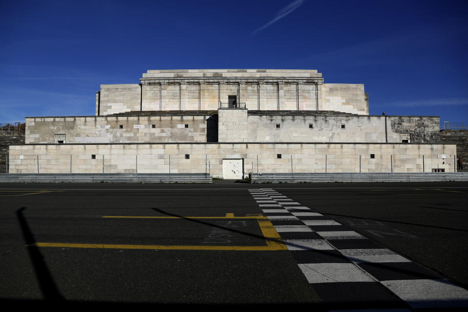 A man stands of the main tribune near the 'Zeppelinfeld' at the 'Reichsparteigelande', Nazi Party Rally Grounds, in Nuremberg, Germany, Wednesday, Nov. 18, 2020. Germany marks the 75th anniversary of the landmark Nuremberg trials of several Nazi leaders and in what is now seen as the birthplace of a new era of international law on Friday, Nov. 20, 2020. (AP Photo/Matthias Schrader)