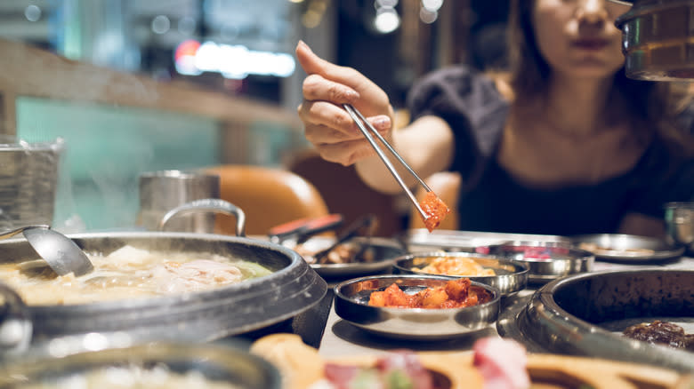 A woman using chopsticks to serve food on Korean BBQ side plates