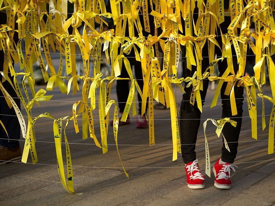 A woman puts a yellow ribbon with others at a memorial for victims of the 'Sewol' ferry disaster in Seoul on May 1, 2014.