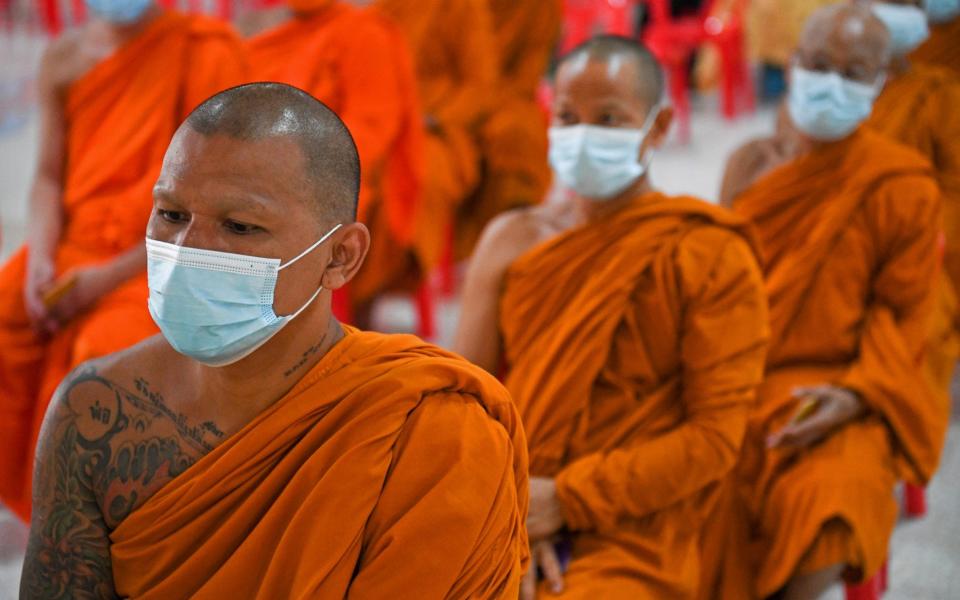 Buddhist monks wearing face masks wait to receive a dose of China's Sinovac coronavirus disease vaccine at a temple - REUTERS/Chalinee Thirasupa