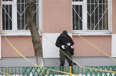 A security service member uses a mine and metal detector as he works near the building of a high school, where a shooting incident has occurred, on the outskirts of Moscow