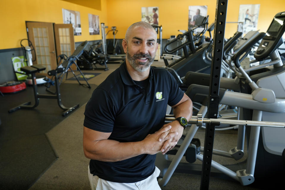 Push Pedal Pull sales representative Luke Reiland poses in a store showroom, Thursday, Sept. 30, 2021, in Ankeny, Iowa. A growing number of school districts in the U.S. are using federal pandemic funding on athletics projects. The high school weight room overhaul in Story City, Iowa, is being done by Push Pedal Pull, a South Dakota company that also is taking on similar projects in that state and in Nebraska. (AP Photo/Charlie Neibergall)