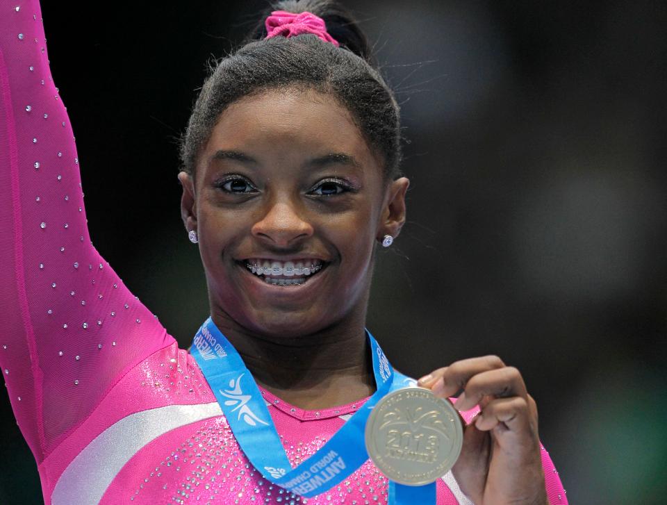 Simone Biles shows her gold medal after the all-around final at the World Championships in Antwerp, Belgium, on Oct. 4, 2013. She's now completing a comeback in the 2023 World Championship in the same city.