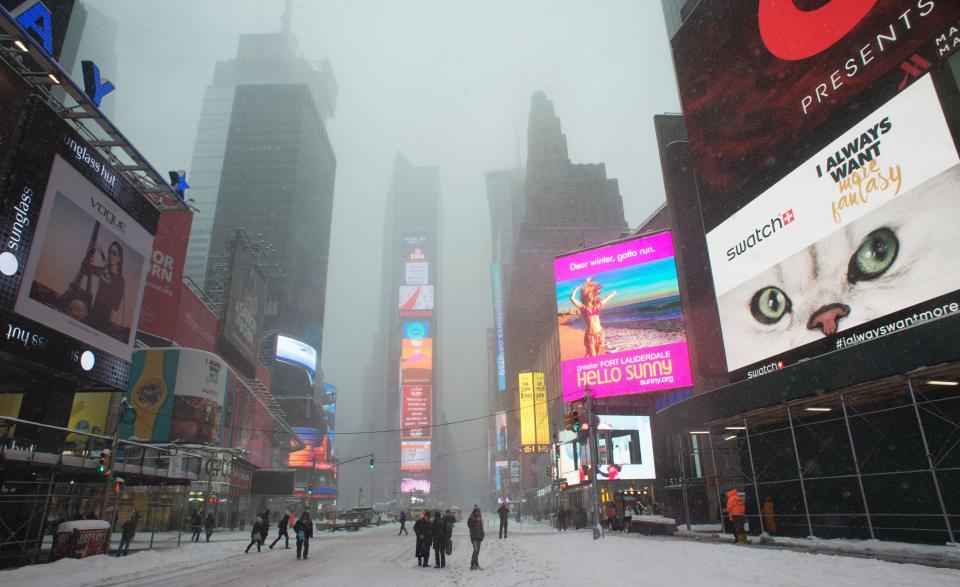 People walk on the snow covered streets of Times Square January 23, 2016 in New York. A deadly blizzard with bone-chilling winds and potentially record-breaking snowfall slammed the eastern US on January 23, as officials urged millions in the storm's path to seek shelter -- warning the worst is yet to come. US news reports said at least eight people had died by late Friday from causes related to the monster snowstorm, which is expected to last until early Sunday.&nbsp;