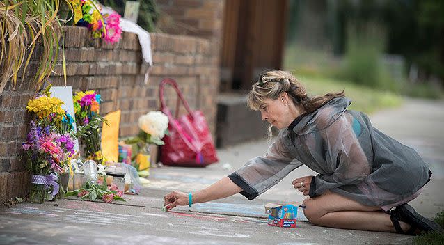 A local woman writes on a memorial near the scene of the shooting. Photo: AAP