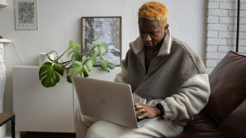  Person using a MacBook sat on sofa. 