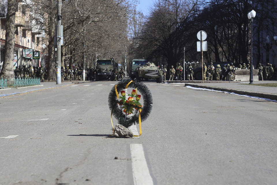 A ceremonial wreath is placed in a street as Russian army soldiers stand near their trucks during a rally against the Russian occupation in Kherson, Ukraine, Sunday, March 13, 2022. Ever since Russian forces took the southern Ukrainian city of Kherson in early March, residents sensed the occupiers had a special plan for their town. Now, amid a crescendo of warnings from Ukraine that Russia plans to stage a sham referendum to transform the territory into a pro-Moscow "people's republic," it appears locals guessed right. (AP Photo/Petros Giannakouris)