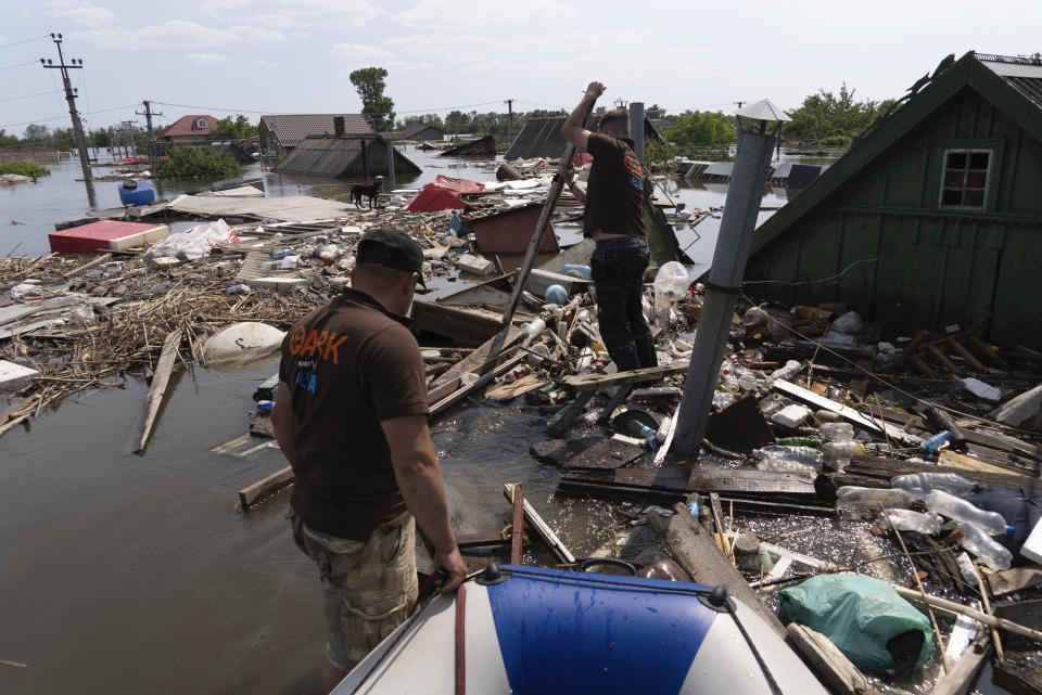 Animal rescuers make their way through floating debris to rescue a dog in the flooded area after the dam collapse in Kherson, Ukraine, Thursday, June 8, 2023. (AP Photo/Vasilisa Stepanenko)