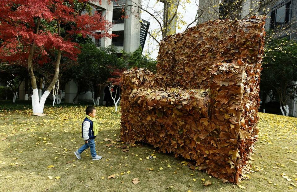 <p>Ein Kind geht vor einer Laubinstallation entlang. Studenten in China haben die Blätter in Form eines Sofas arrangiert, um Aufmerksamkeit für das Thema Umweltschutz zu erregen. (Bild: China Daily via Reuters) </p>