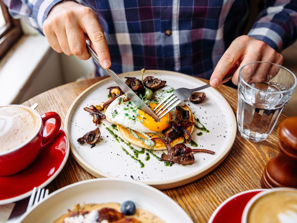 A person eating eggs with mushrooms.