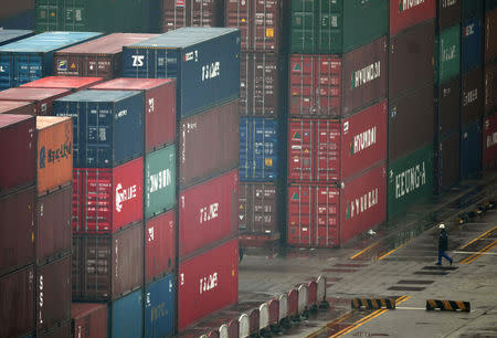 FILE PHOTO: A worker walks amongst shipping containers at the port of Shanghai January 19, 2011. REUTERS/Carlos Barria
