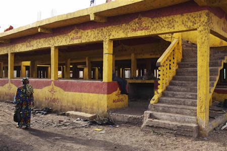 A women walks past an abandoned marketplace in Bamako February 27, 2014. REUTERS/Joe Penney