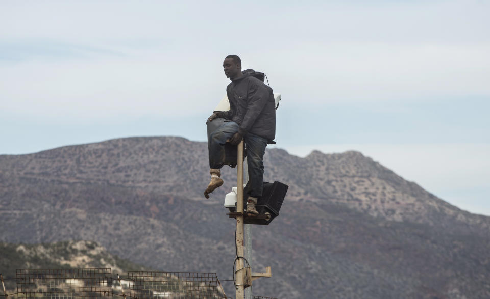 A sub-Saharan migrant sits on top of a pole set in a metallic fence that divides Morocco and the Spanish enclave of Melilla, Thursday, April 3, 2014. Spanish and Moroccan police have thwarted a fresh attempt by dozens of African migrants to try to scale border fences to enter the Spanish enclave of Melilla. Thousands of sub-Saharan migrants seeking a better life in Europe are living illegally in Morocco and regularly try to enter Melilla in the hope of later making it to mainland Spain. (AP Photo/Santi Palacios)