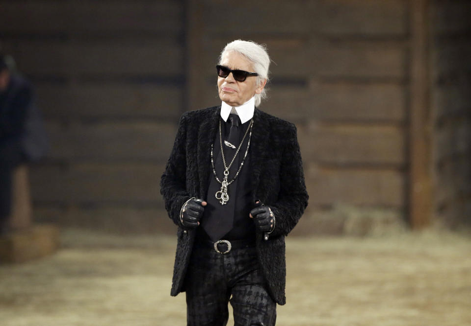 Designer Karl Lagerfeld takes a bow at the end of his Metiers d'Art fashion show in Dallas on Dec. 10, 2013. Lagerfeld, whose trademark white ponytail, high starched collars and dark enigmatic glasses dominated high fashion for the last 50 years, died on Feb. 19. He was 85. (AP Photo/Tony Gutierrez)