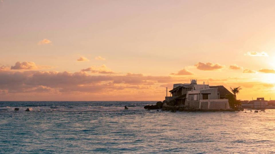 Glimpse of Isla Mujeres, Costa Mujeres’ island in the Caribbean sea, lit up by a sunset.