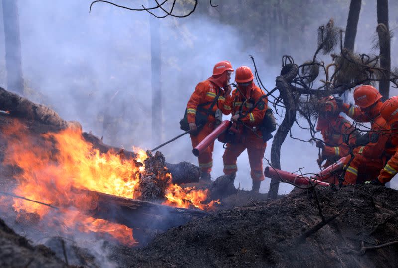 Firefighters work on extinguishing a forest fire that started near Xichang in Liangshan prefecture