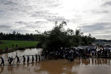 Rohingya cross a swollen river at a refugee camp in Cox's Bazar, Bangladesh, September 17, 2017. REUTERS/Cathal McNaughton