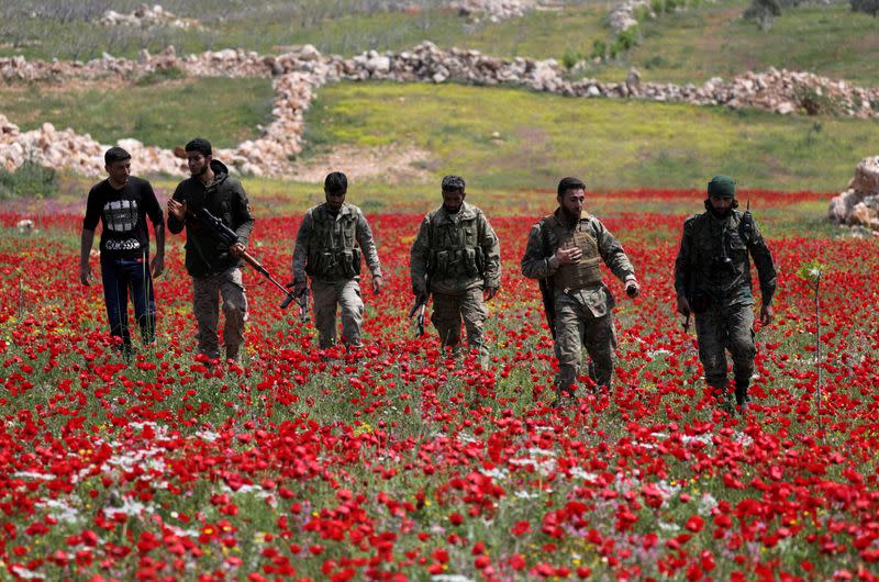 FILE PHOTO: Turkey-backed Syrian rebel fighters walk in a field of flowers in Jabal al-Zawiya