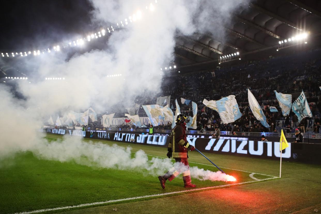 A fire marshal removes a flare thrown onto the pitch. (Paolo Bruno/Getty Images)