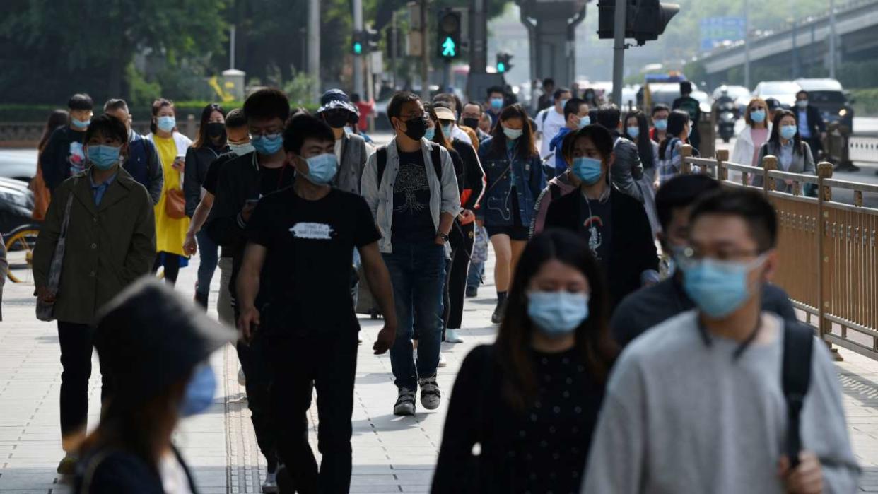 Le 11 mai 2021, des promeneurs marchent sur un trottoir à l’heure de pointe du matin à Pékin.