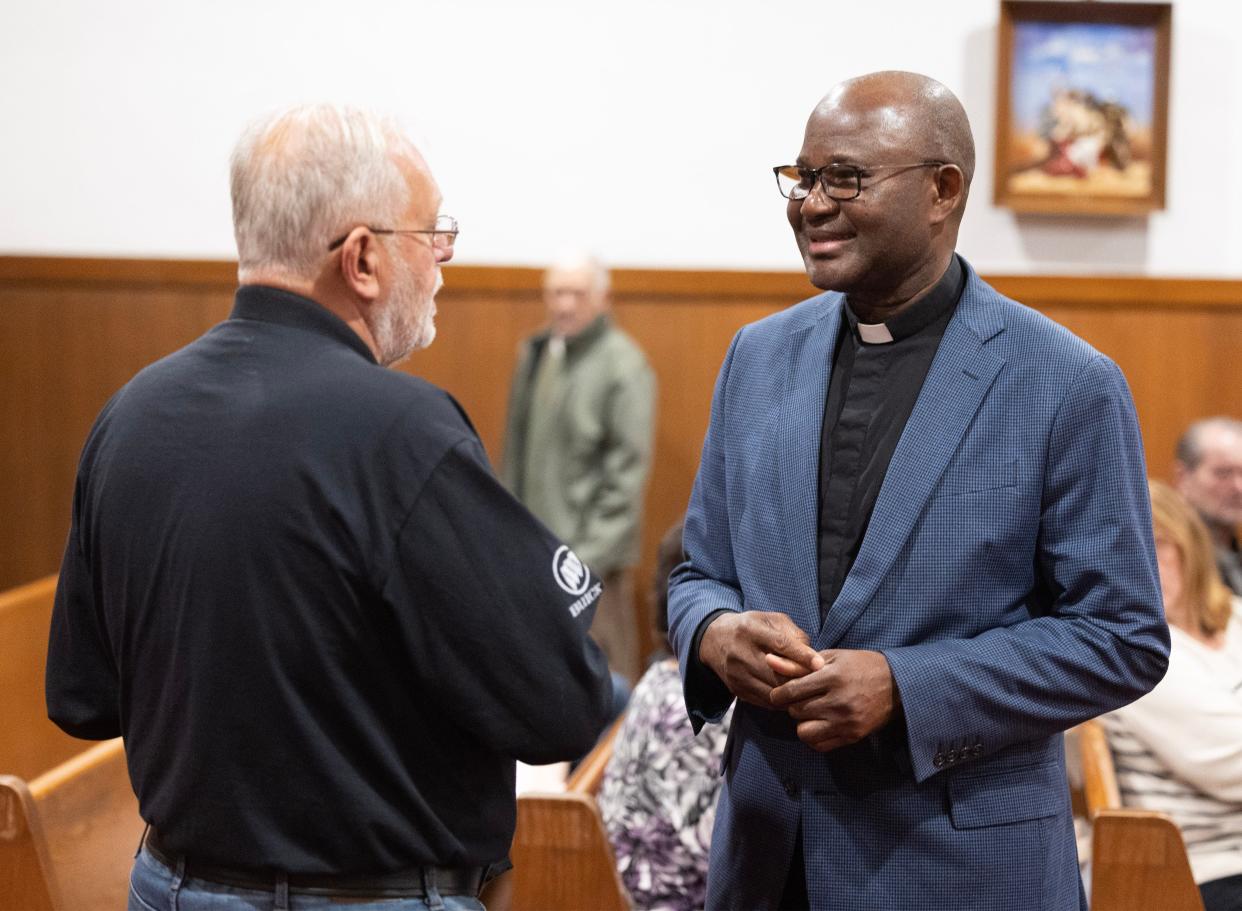 The Rev. Benson Okpara, right, a former pastor of St. Mary's Catholic Church in Canton, speaks Monday, Nov. 6, 2023, with parishioner Rick Cuenot at the church's last Mass.