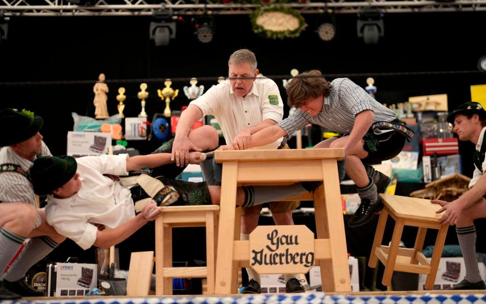 Men dressed in traditional clothes try to pull the opponent over a marked line on the table at the Fingerhakeln championships, in Bernbeuren, Germany on Sunday