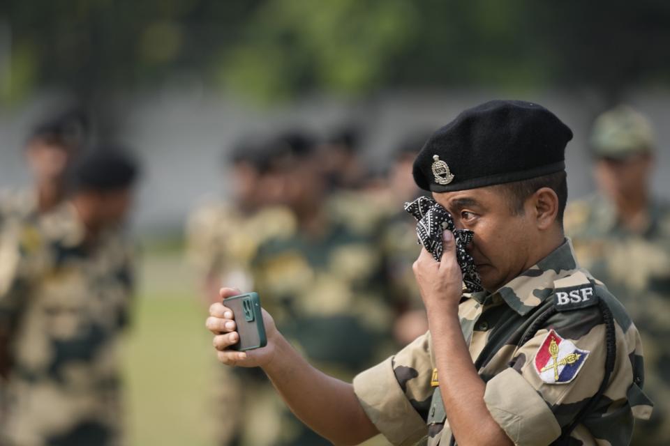 An Indian Border Security Force (BSF) soldier wipes his tears as he takes a video of a wreath-laying ceremony for his colleague Lal Fam Kima during at the BSF headquarters in Jammu, India, Thursday, Nov.9, 2023. Lal Fam Kima was killed as Indian and Pakistani soldiers exchanged gunfire and shelling along their highly militarized frontier in disputed Kashmir. (AP Photo/Channi Anand)