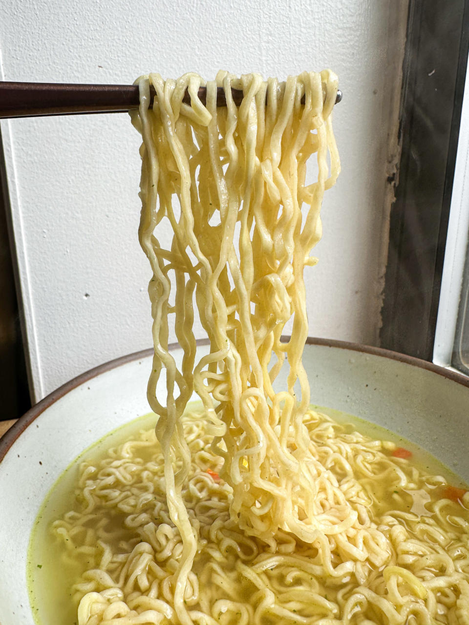 holding up cup noodles noodles in bowl