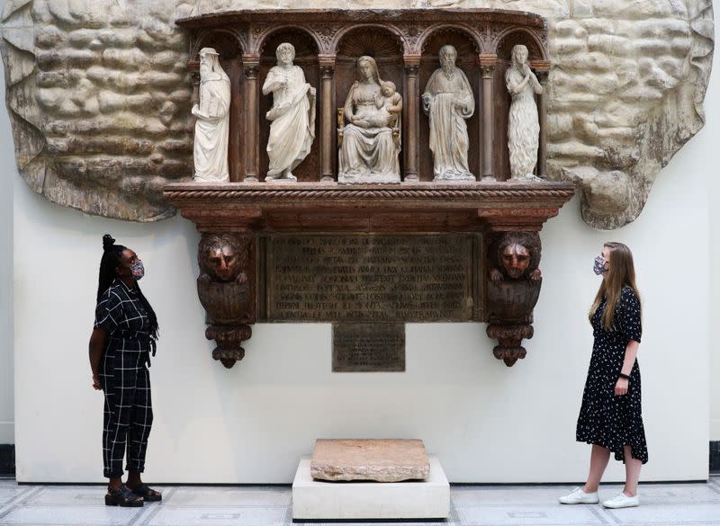 Museum gallery assistants pose for members of the media in front of the 'Monument of Marchese Spinetta Malaspina' during preparations to reopen the Victoria & Albert (V&A) Museum, in London