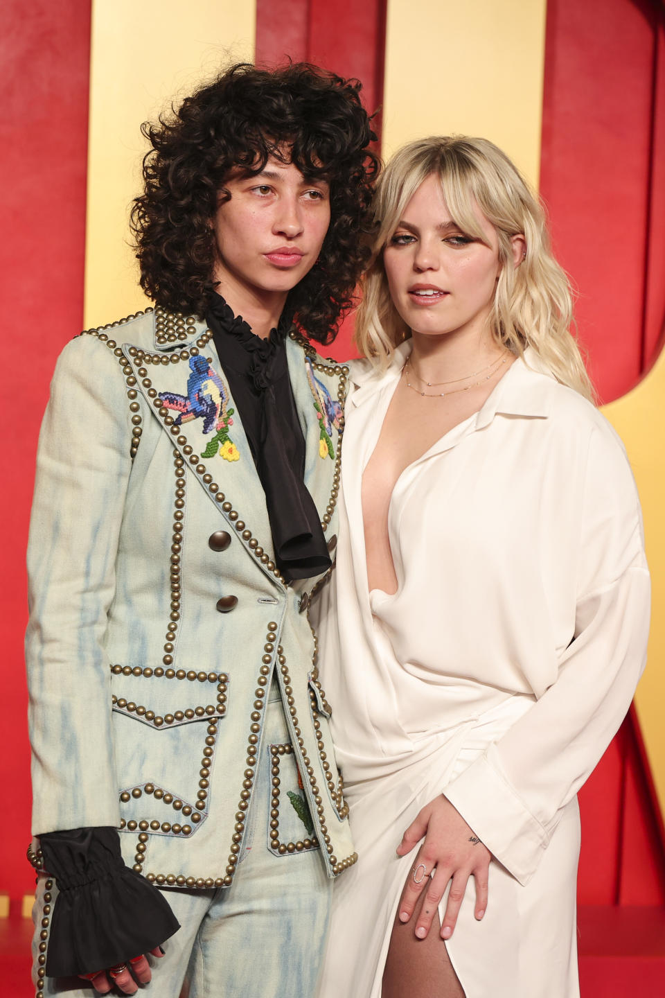 Towa in a decorated light suit with ruffles, Reneé in an outfit with an open white neckline and high thigh slit