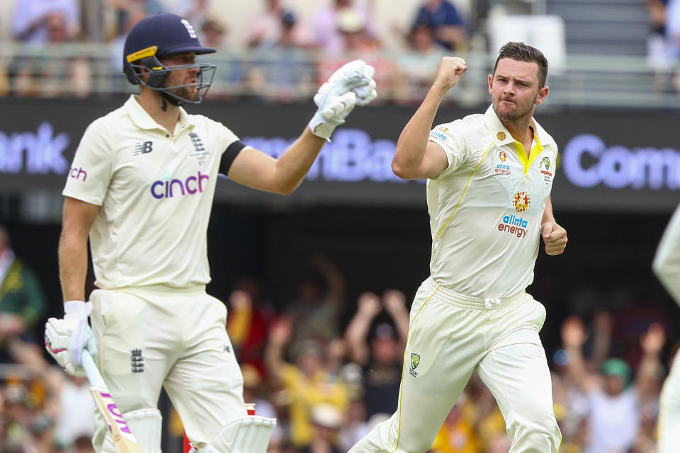 Australia's Josh Hazlewood, right, celebrates after taking the wicket of England's Dawid Malan, left, during day one of the first Ashes cricket test at the Gabba in Brisbane, Australia, Wednesday, Dec. 8, 2021. (AP Photo/Tertius Pickard)