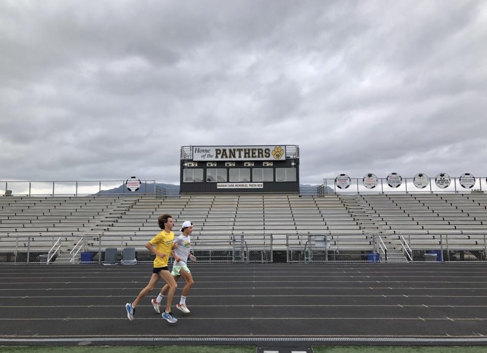 Colin Sahlman, left in yellow, and teammate Lex Young train on the Newbury Park High track.