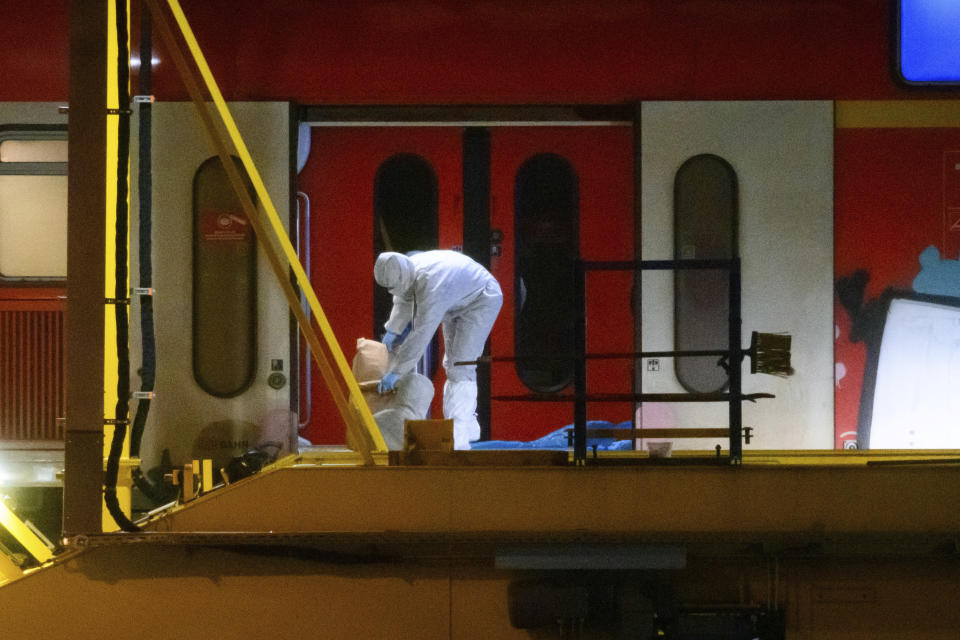 Investigators in white protective suits work in the regional train that had been driven onto a siding in Neumunster, Germany, Wednesday, Jan. 25, 2023. Germany's Federal Police force said a suspect used a knife to attack several passengers shortly before the regional train traveling from Kiel to Hamburg arrived at the Brokstedt station. (Jonas Walzberg/dpa via AP)