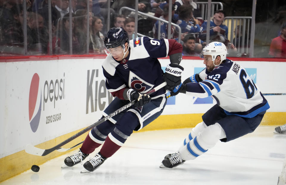 Colorado Avalanche center Evan Rodrigues, left, collects the puck as Winnipeg Jets right wing Nino Niederreiter defends in the second period of an NHL hockey game Thursday, April 13, 2023, in Denver. (AP Photo/David Zalubowski)