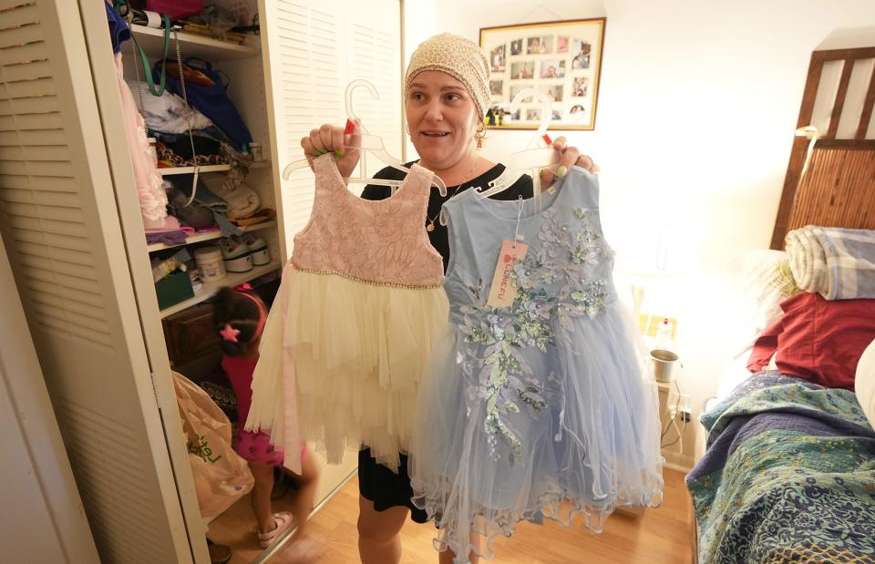 Liana Curbelo holds up dresses for her daughter Sky’s upcoming birthday party.