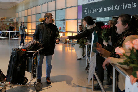 Laura Atlas Kravitz, an opponent of U.S. President Donald Trump's executive order travel ban, hands a flower to an arriving international traveler at Logan Airport in Boston, Massachusetts, U.S. February 3, 2017. REUTERS/Brian Snyder