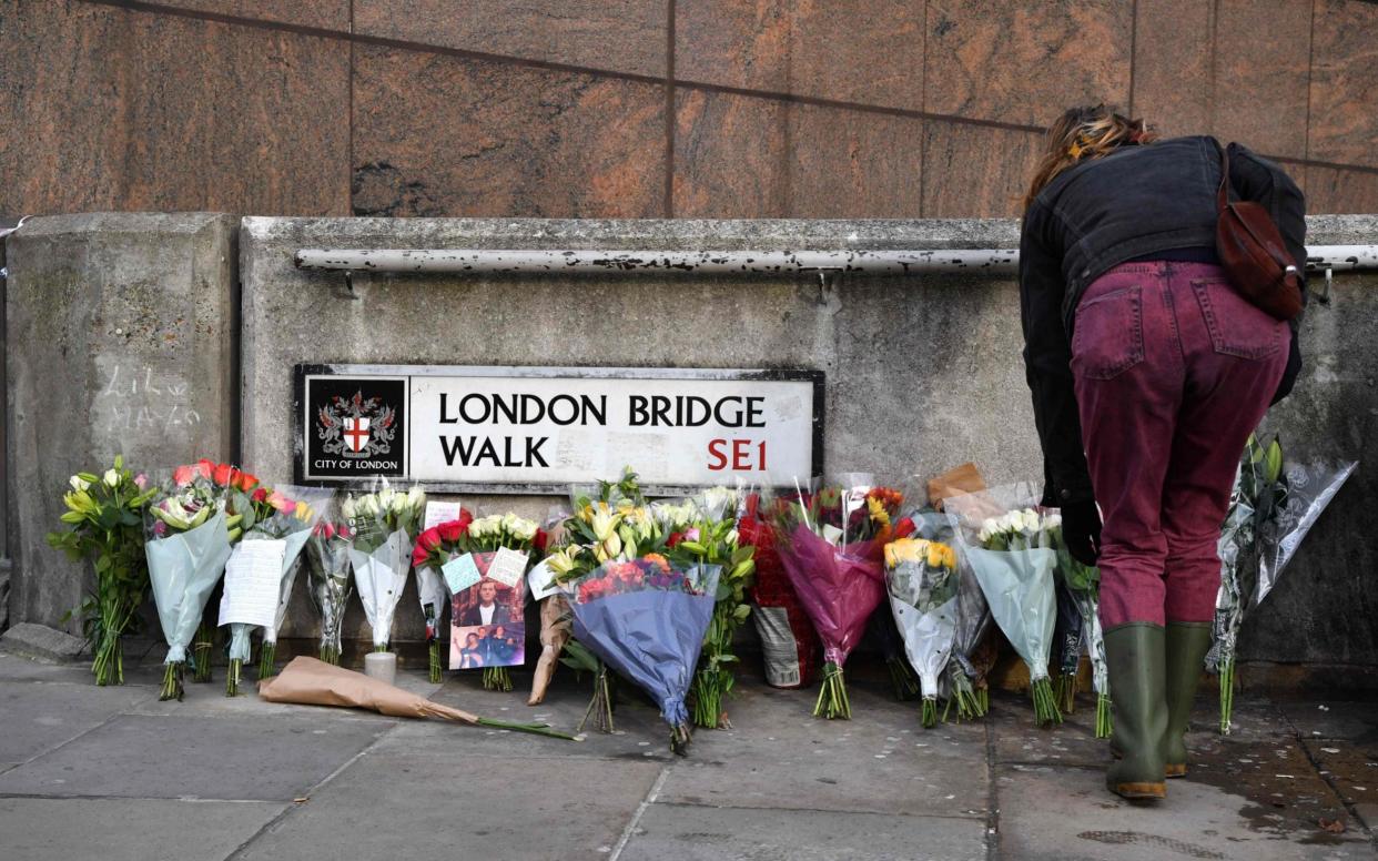 A woman places flowers with other floral tributes close to London Bridge in the City of London - AFP