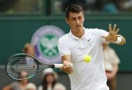 Bernard Tomic of Australia hits a shot during his match against Novak Djokovic of Serbia at the Wimbledon Tennis Championships in London, July 3, 2015. REUTERS/Suzanne Plunkett