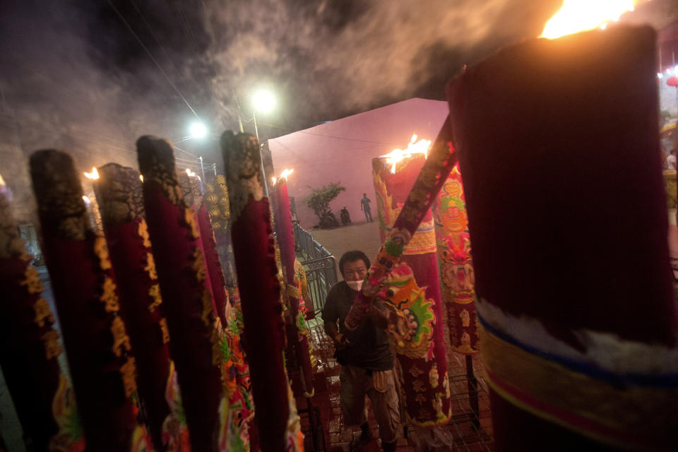 An ethnic Chinese man wearing lights joss stick during the Lunar New Year celebration at a temple in Medan, North Sumatra, Indonesia, Friday, Feb. 12, 2021. (AP Photo/Binsar Bakkara)